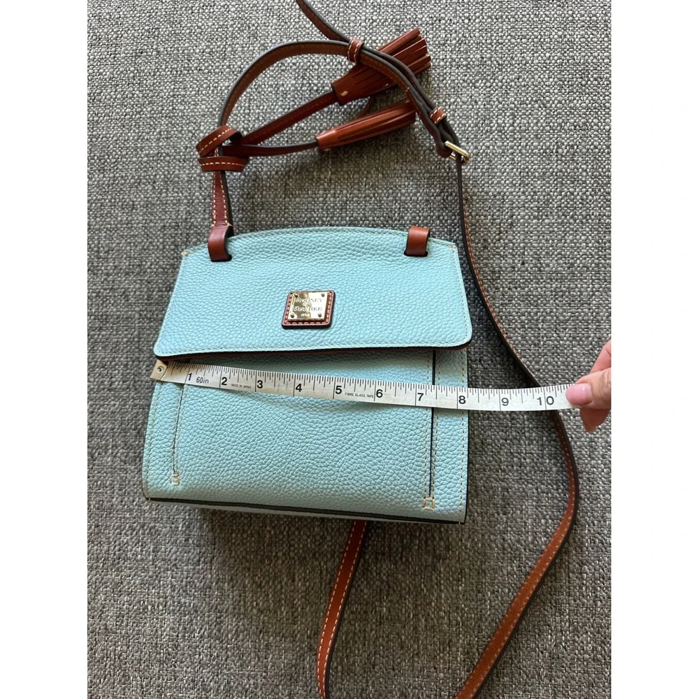 This is a Dooney & Bourke Pebble Grain East/West Flap Crossbody in a light blue